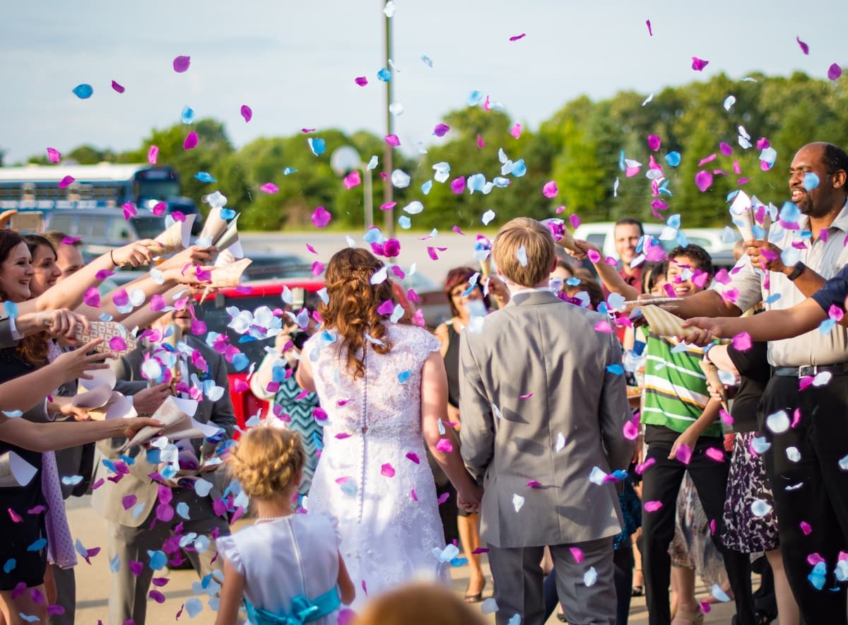 Bruidspaar omringd door gasten die confetti gooien na de ceremonie